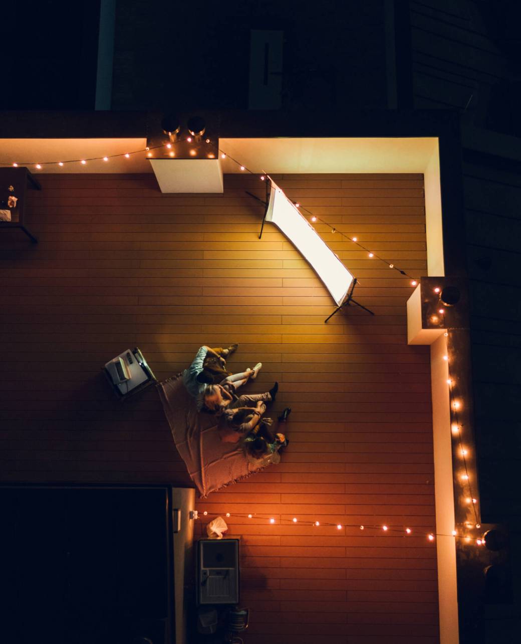 Aerial shot of four friends hanging out and watching movie on a rooftop