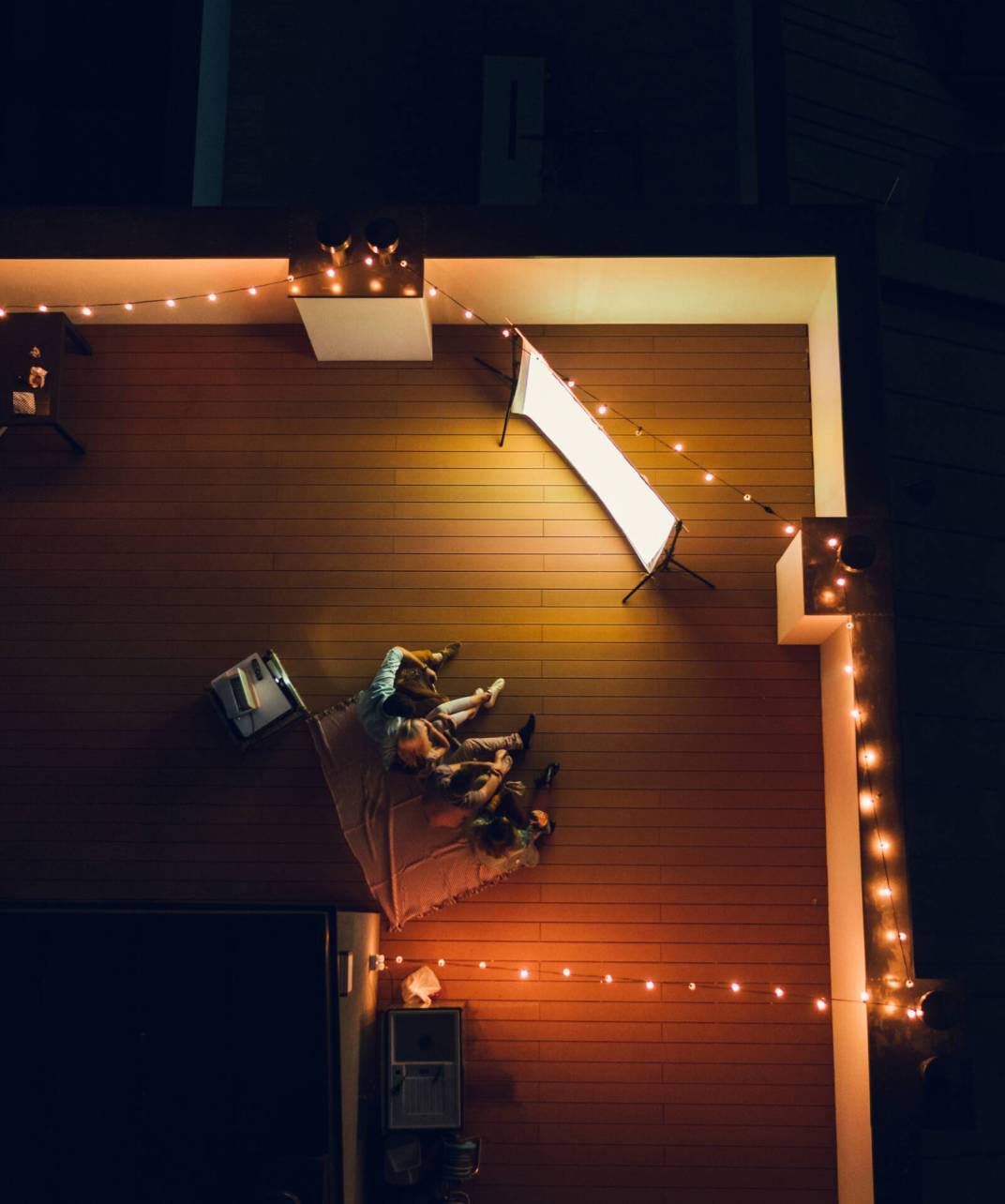 Aerial shot of four friends hanging out and watching movie on a rooftop